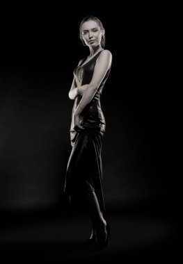 Güzel, seksi esmer kız siyah arka planda poz veriyor. Gece elbisesiyle.