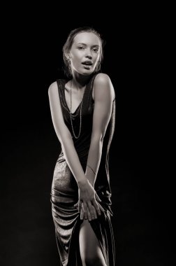 Güzel, seksi esmer kız siyah arka planda poz veriyor. Gece elbisesiyle.