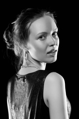 Güzel, seksi esmer kız siyah arka planda poz veriyor. Gece elbisesiyle.