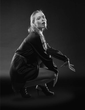 Güzel, seksi esmer kız siyah arka planda poz veriyor. Gece elbisesiyle.