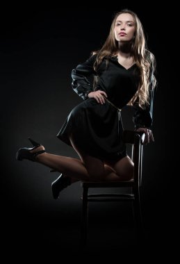 Güzel, seksi esmer kız siyah arka planda poz veriyor. Gece elbisesiyle.