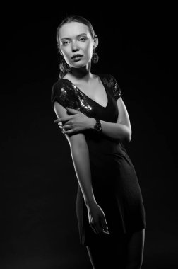 Güzel, seksi esmer kız siyah arka planda poz veriyor. Gece elbisesiyle.