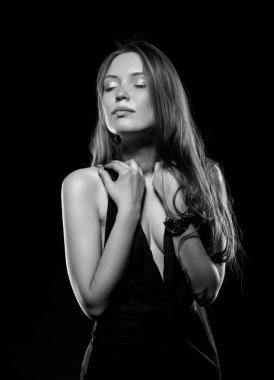 Güzel, seksi esmer kız siyah arka planda poz veriyor. Gece elbisesiyle.