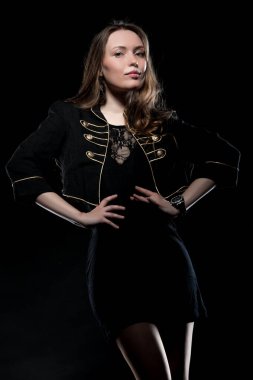 Güzel, seksi esmer kız siyah arka planda poz veriyor. Gece elbisesiyle.