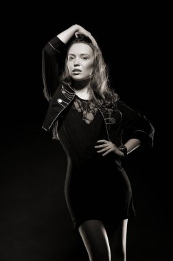 Güzel, seksi esmer kız siyah arka planda poz veriyor. Gece elbisesiyle.