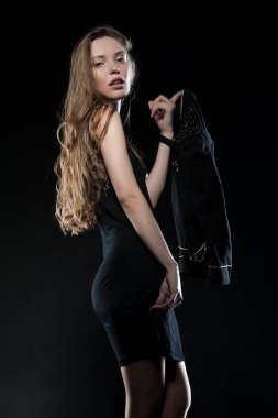 Güzel, seksi esmer kız siyah arka planda poz veriyor. Gece elbisesiyle.