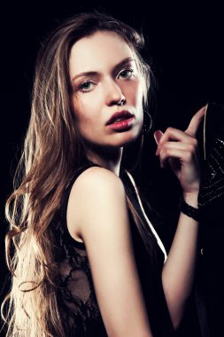 Güzel, seksi esmer kız siyah arka planda poz veriyor. Gece elbisesiyle.