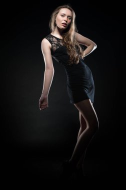 Beautiful sexy brunette girl posing on a black background in an evening dress