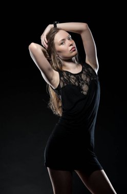 Güzel, seksi esmer kız siyah arka planda poz veriyor. Gece elbisesiyle.