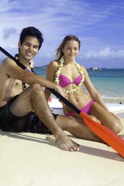 Couple on the beach with paddleboards — Stock Photo, Image
