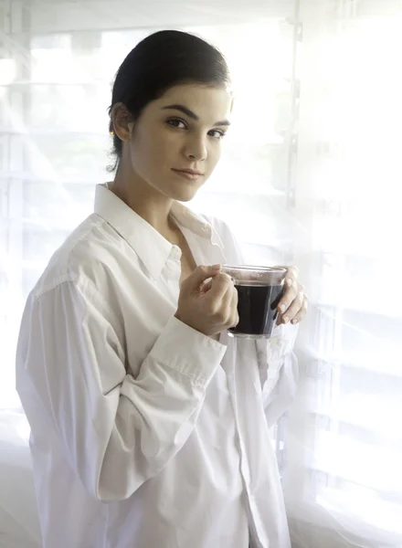 Vrouw door heldere venster met koffie. — Stockfoto