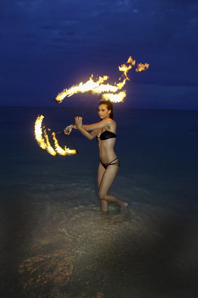 Kvinna med eld på stranden på natten — Stockfoto