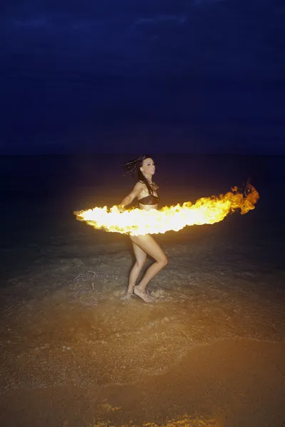 Kvinna med eld på stranden på natten — Stockfoto