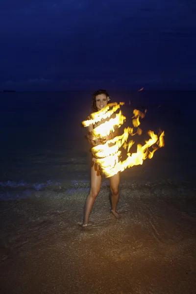 Kvinna med eld på stranden på natten — Stockfoto