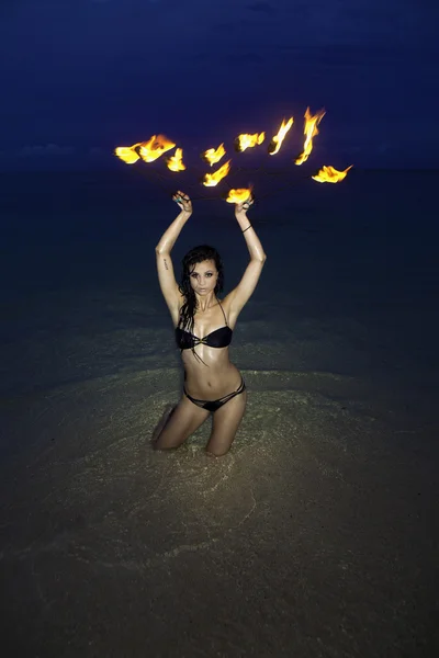 Frau mit Feuer am Strand in der Nacht — Stockfoto