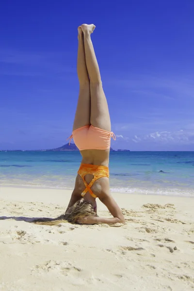 Blond meisje in bikini doen yoga op het strand — Stockfoto