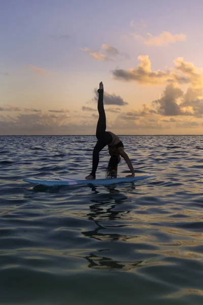 Mujer haciendo yoga en una tabla de paddle —  Fotos de Stock