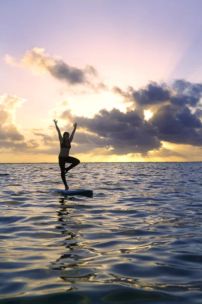 Mujer haciendo yoga en una tabla de paddle —  Fotos de Stock