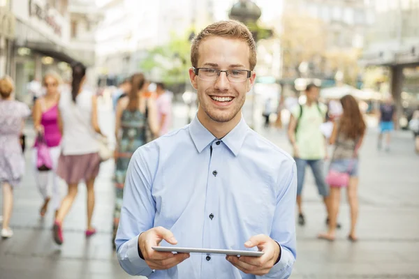Młody uśmiechający się człowieka z komputerem typu tablet na ulicy — Zdjęcie stockowe