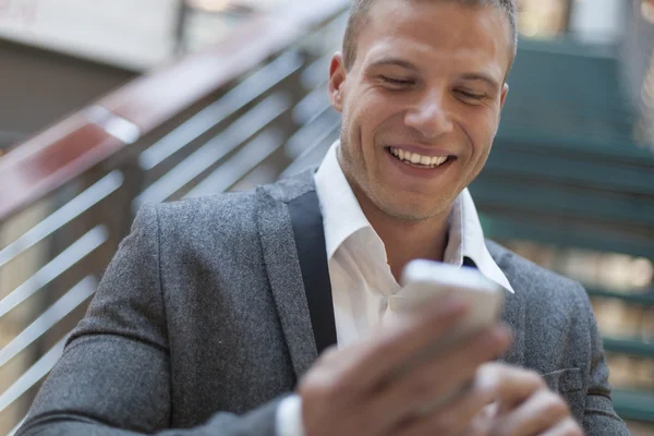 Les hommes lisent des SMS sur son smartphone dans un immeuble d'affaires — Photo