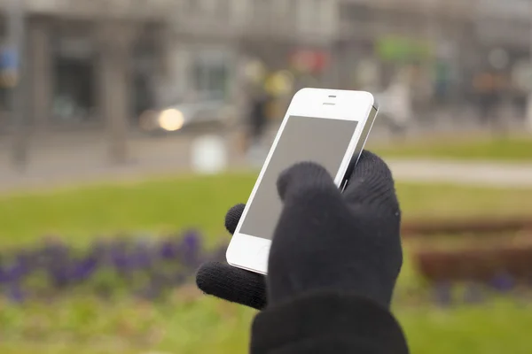 Smartphone in hand met handschoenen — Stockfoto