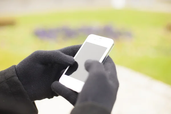 Smartphone i hand med handskar — Stockfoto