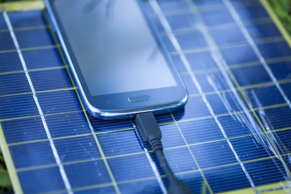 Зарядка мобільного телефону за допомогою сонячного зарядного пристрою — стокове фото
