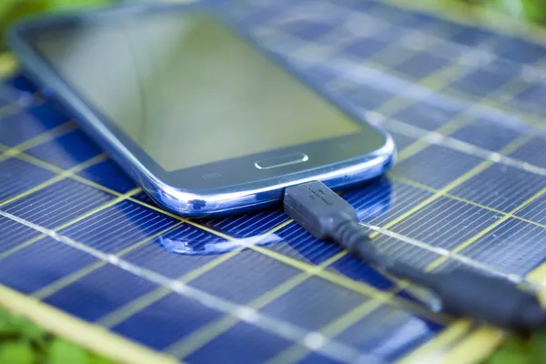 Зарядка смартфона за допомогою сонячного зарядного пристрою — стокове фото