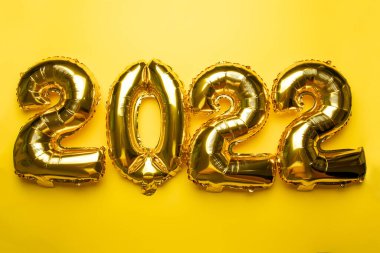 2022 Altın folyo balonundan sarı arkaplan fotoğrafına yeni yıl kavramı