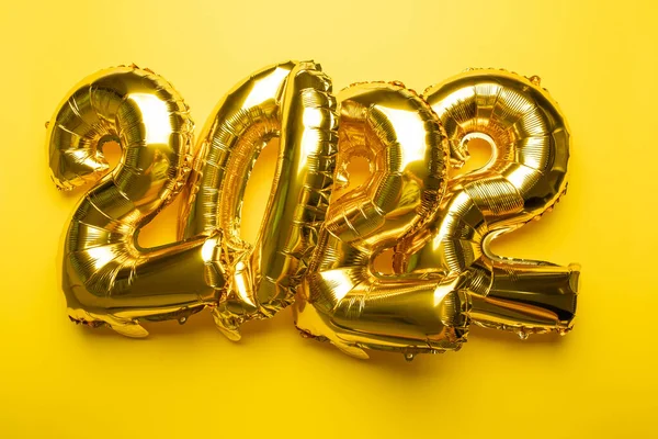 2022年金箔气球在黄色背景照片上的新年概念 — 图库照片
