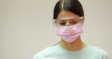 Koruyucu eldivenler giyen ve cam şişeyi iğne sıvısıyla tutan bir doktor. Grip ve koronavirüse karşı aşı. 4K stok video