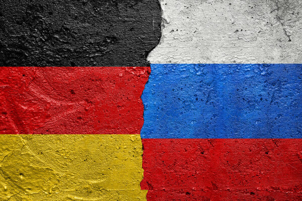 Germany vs Russia - Cracked concrete wall painted with a Germans flag on the left and a Russian flag on the right