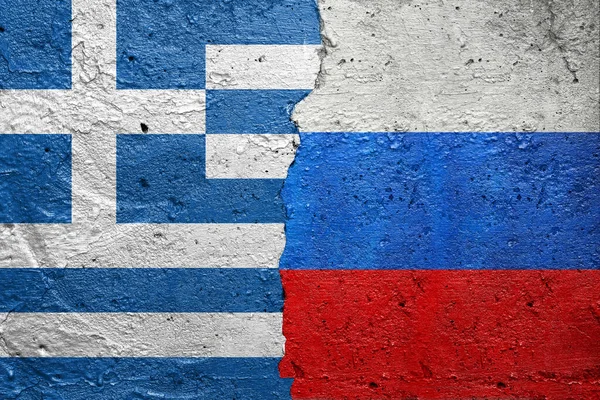 Greece and Russia - Cracked concrete wall painted with a Greek flag on the left and a Russian Federation flag on the right