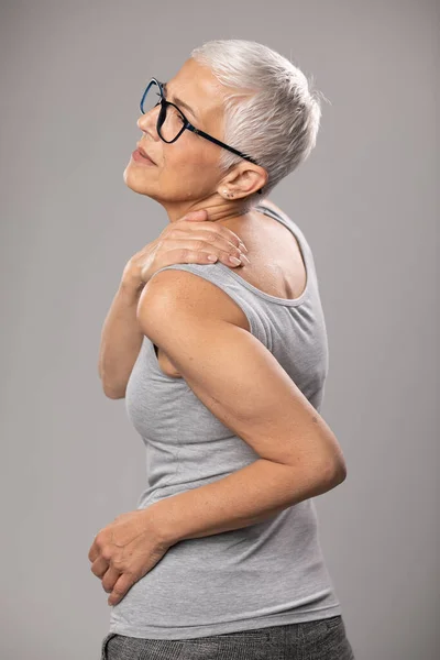 Shoulder and neck pain, backache, senior old woman with short gray hair and glasses show body and spinal muscle problems