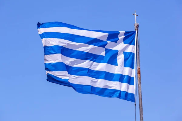 A large Greek flag on a flagpole near the Greece state border on wind