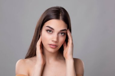 Temiz ciltli güzel bir genç kadın. Doğal çıplak makyajlı ve yüzüne dokunan güzellik modeli portresi. Spa, cilt bakımı ve sağlık. Yakın çekim, kopyalanma alanı.