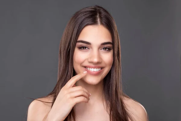 Beautiful smiling woman with clean perfect skin. Portrait of beauty model with natural nude make up and touching her lips. Spa, skincare and wellness. Close up, copyspace.