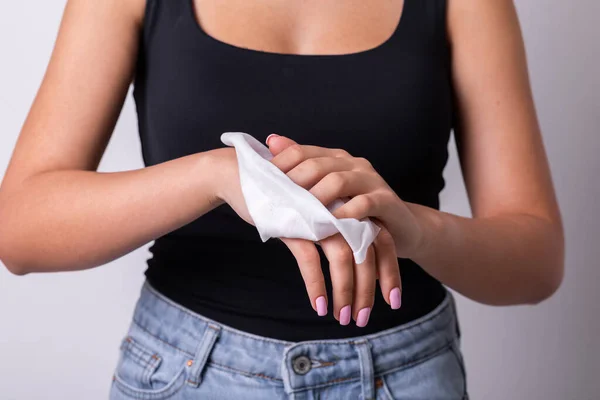 Woman in black tank top with light pink nails cleaning hands with wet wipes - hygiene procedure and prevention of infectious diseases stock photo