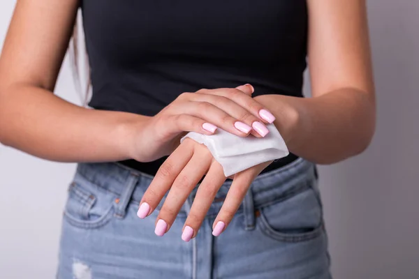 Woman in black tank top with light pink nails cleaning hands with wet wipes - hygiene procedure and prevention of infectious diseases stock photo