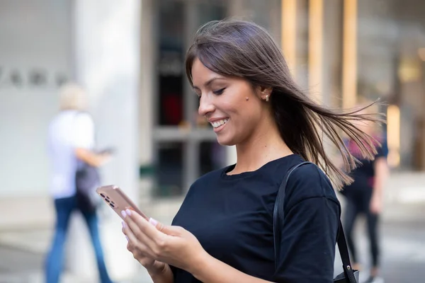 Vacker Leende Kvinna Svart Skjorta Sms Smartphone Gatan Centrum — Stockfoto