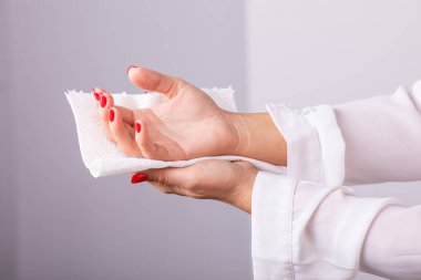 Kadın ellerini beyaz kağıt mendille temizliyor.