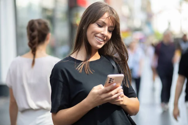 Vacker Leende Kvinna Svart Skjorta Sms Smartphone Gatan Centrum — Stockfoto