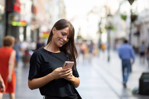 Vacker Leende Kvinna Svart Skjorta Sms Smartphone Gatan Centrum — Stockfoto