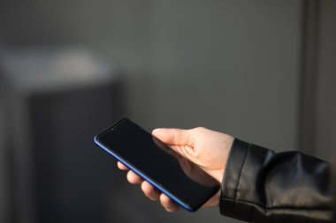 Cep telefonlu, internet ya da sosyal ağlarda arama yapan, arka planda bulanık erkek elinin yakın plan görüntüsü