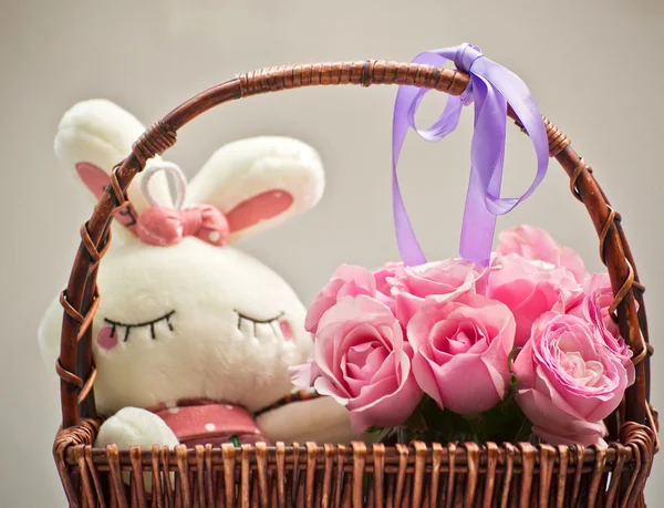 Rosas cor-de-rosa em uma cesta e brinquedo de coelho branco — Fotografia de Stock