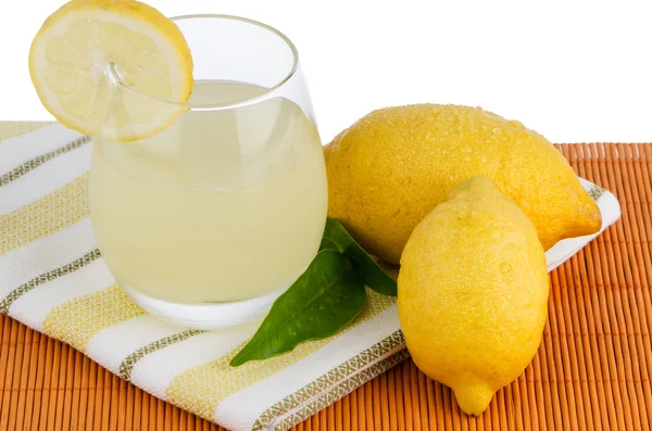 Чашка лимонного сока и свежие лимоны — стоковое фото