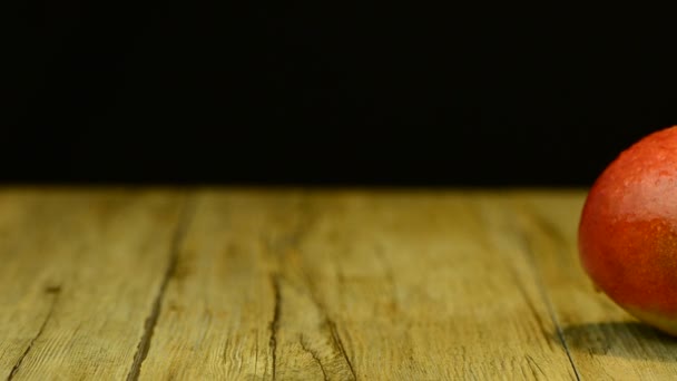Mango de manzana y jugo deslizándose sobre mesa de madera sobre fondo negro — Vídeos de Stock