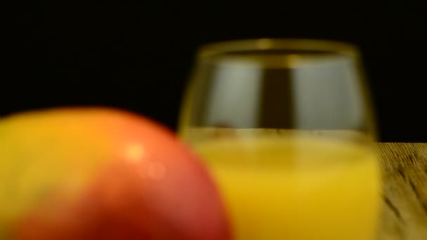 Mango de manzana y jugo deslizándose sobre mesa de madera sobre fondo negro — Vídeos de Stock