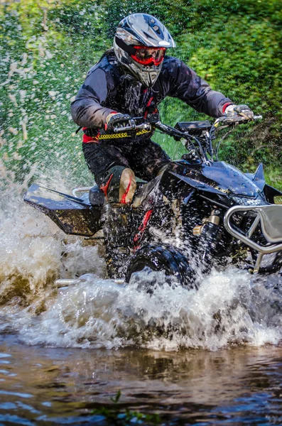 Cavaliere quad attraverso il flusso d'acqua — Foto Stock