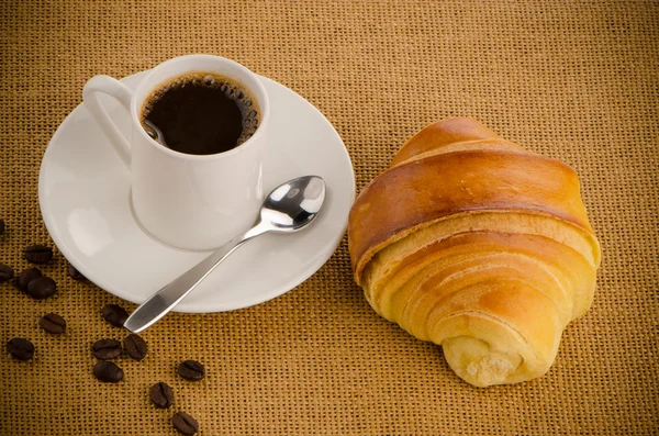 Kopje zwarte koffie en een croissant — Stockfoto